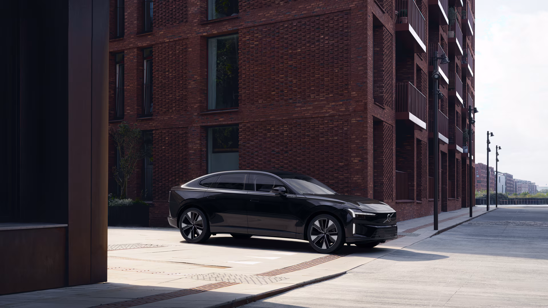 Чорний Volvo ES90 біля сучасної цегляної будівлі