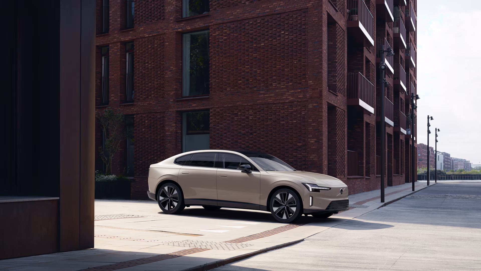 Бежевий Volvo ES90 біля сучасної цегляної будівлі