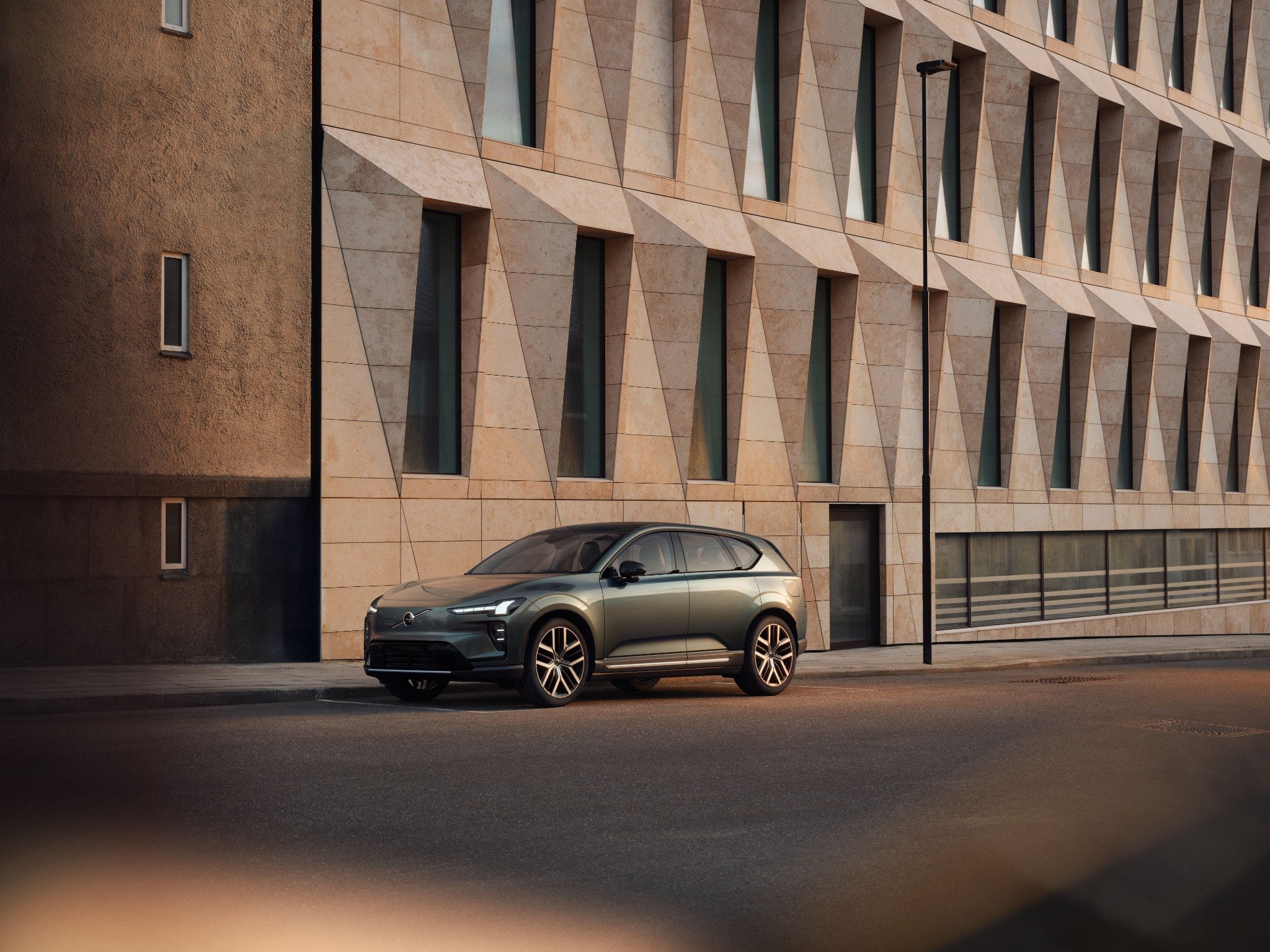 Сірий Volvo кросовер біля сучасного фасаду будівлі